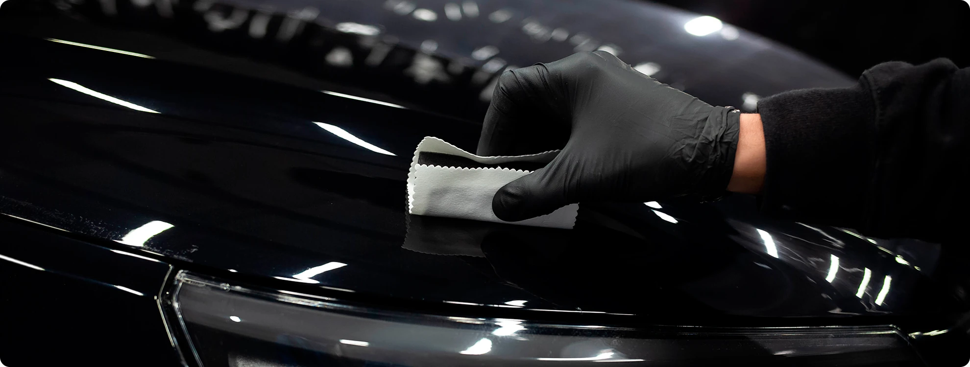 One2one brengt keramische coating aan op de lak van een zwarte auto.