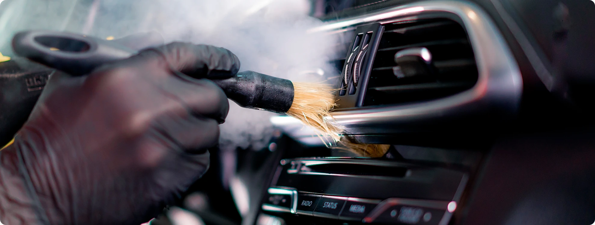 Stoomreiniging van ventilatieroosters tijdens een professionele auto interieur reiniging.